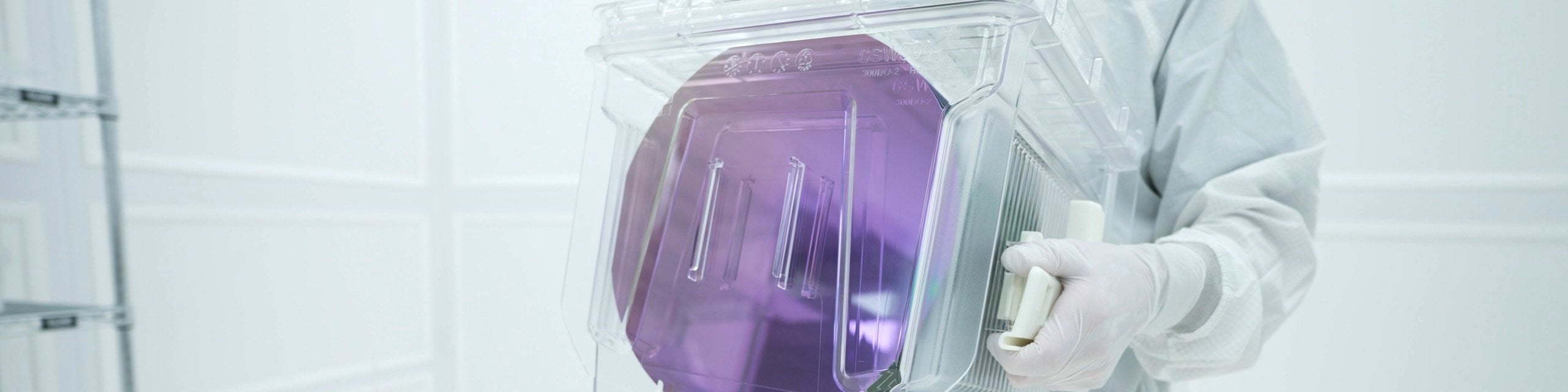 A Rogue Valley Microdevices technician carrying a wafer lot box through the cleanroom